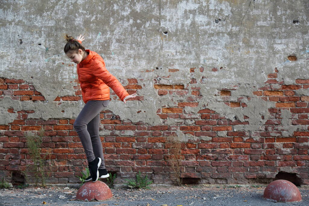Funny active teen gitl against red brick wall outdoor. Selected focus. - Фото, изображение
