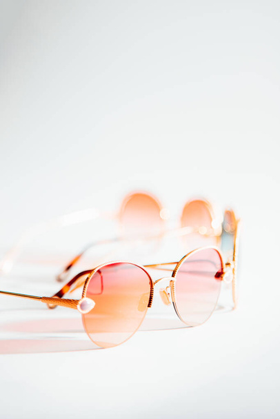 Ένα κάθετο πλάνο από ροζ γυαλιά ηλίου σε χρυσό πλαίσιο σε ένα απομονωμένο φόντο - Φωτογραφία, εικόνα