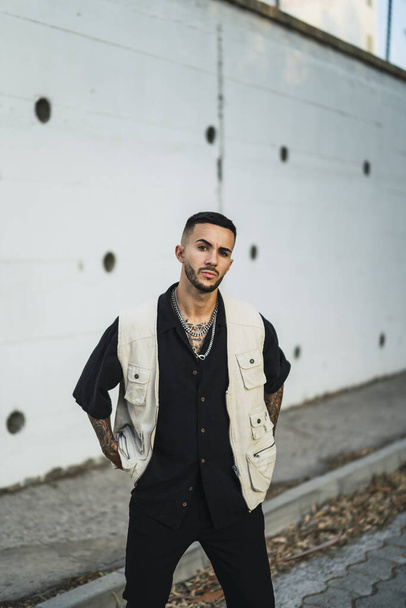 A shallow focus of a young male with tattoos wearing a black shirt with a white jacket - Foto, Imagen