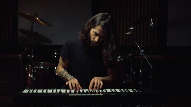 Um homem a tocar teclado no estúdio de música. Cara sorrindo em estúdio de gravação. - Foto, Imagem