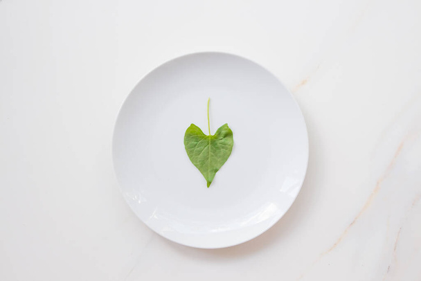 The concept of diet and weight loss, fasting and cleansing the body. Empty white plate on a white marble table. Detox the body with green foods. - Valokuva, kuva
