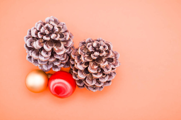 A closeup shot of pine cones and Christmas balls isolated on coral background - Photo, Image