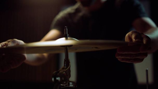 Les mains du batteur installent la cymbale en studio. Musicien torsion vis écrou papillon - Photo, image
