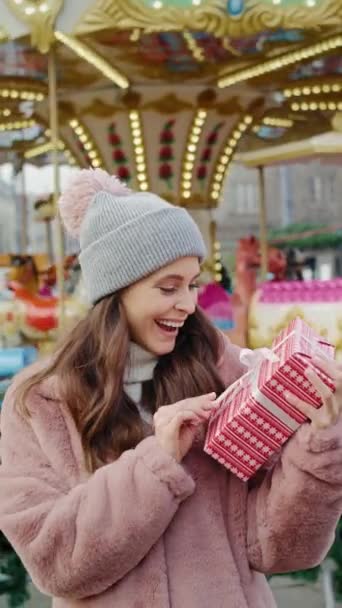 Video einer Frau mit Weihnachtsgeschenk und Karussell im Hintergrund. Aufnahme mit roter Heliumkamera in 8K.  - Filmmaterial, Video