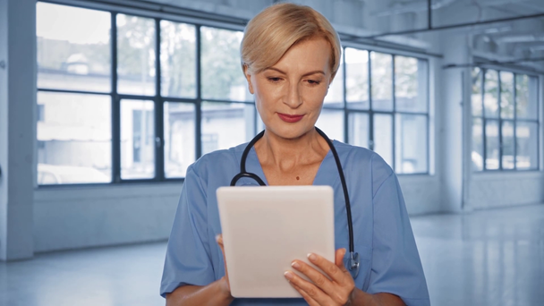 ευτυχής μεσήλικας γιατρός χρησιμοποιώντας ψηφιακή ταμπλέτα στην κλινική  - Πλάνα, βίντεο