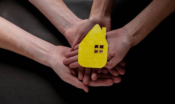 An overhead of a paper cutout of a house on hands  -family concept - 写真・画像