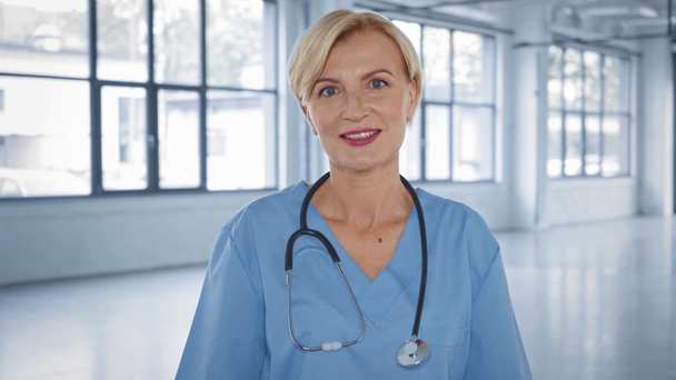 positieve arts van middelbare leeftijd op zoek naar camera in het ziekenhuis  - Video