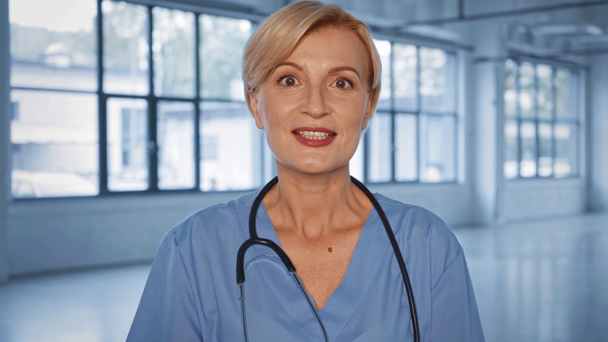 mooie middelbare leeftijd arts praten en kijken naar camera - Video