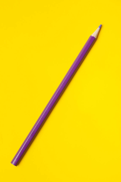 diagonal purple sharp wooden pencil on a bright yellow background, isolated, copy space, mock up - Фото, изображение