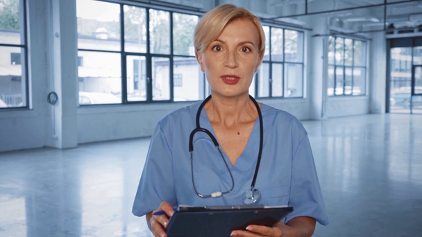 beau médecin d'âge moyen parlant et écrivant prescription dans la clinique  - Séquence, vidéo