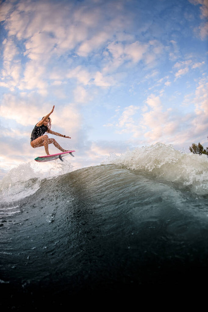 beautiful view of woman jumping over big splashing wave on surf style wakeboard. - Φωτογραφία, εικόνα