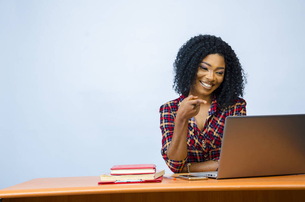 A pretty Afro-American female sitting in front of a laptop and working - Fotoğraf, Görsel