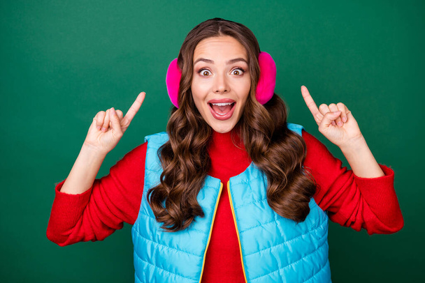 Photo of pretty cute young lady open mouth directing fingers head amazed crazy discount boutique wear pink ear warmers headband blue vest red sweater isolated green color background - Φωτογραφία, εικόνα