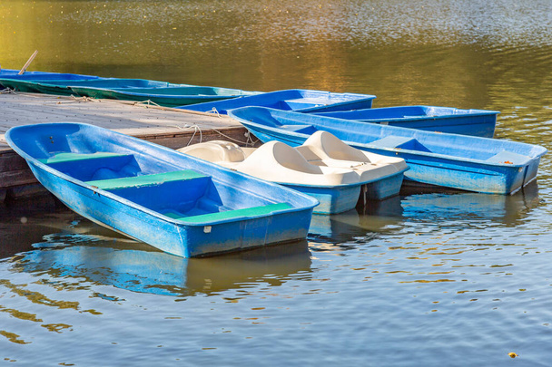 空の青いプラスチックボートと秋の都市の池 - 写真・画像