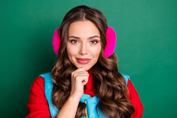 Photo of lovely pretty young lady finger chin confident look thinking best opportunity spend winter wear pink ear warmers blue vest red pullover isolated green color background - Фото, зображення