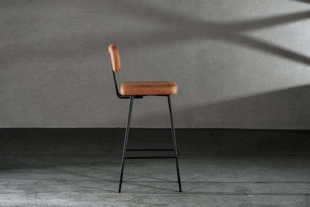 A closeup of a high stool with leather upholstery, on thin legs, loft-style furniture - Fotó, kép