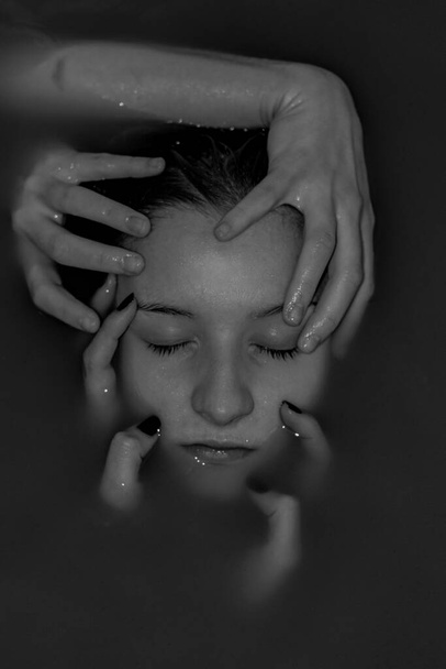 A vertical shot of hands grabbing a female's face in dark water - concept of depression and anxiety - Fotó, kép