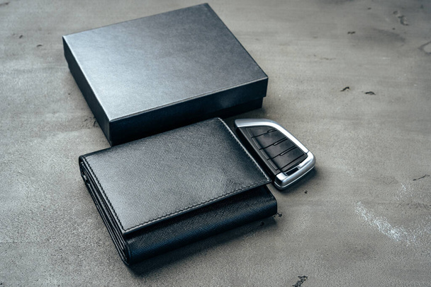 Male leather wallet and car key on dark grey background - Фото, изображение
