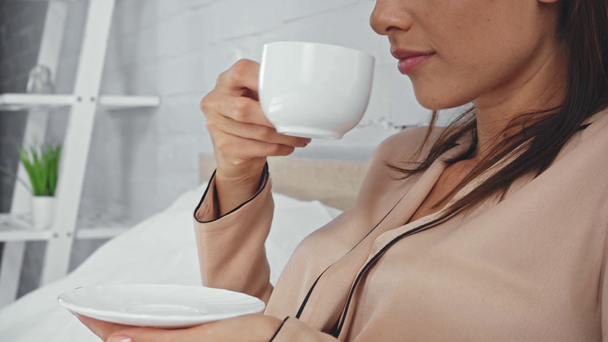 ostříhaný pohled na potěšenou ženu pije kávu v posteli - Záběry, video
