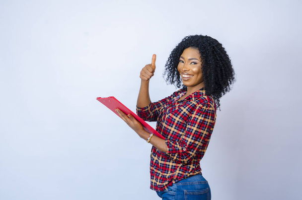 A young cheerful African female holding a document folder - Foto, Imagem
