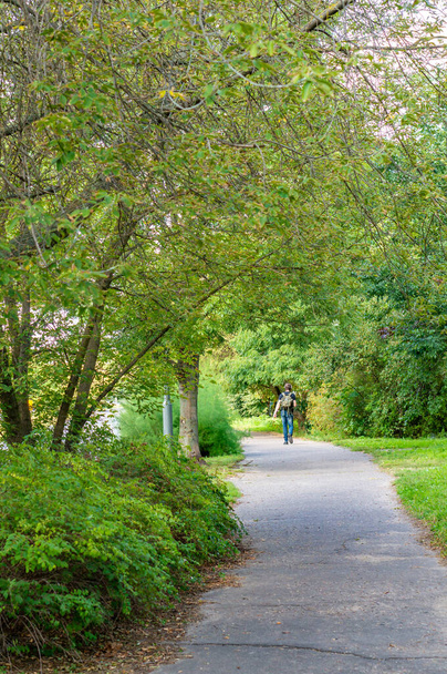 POZNA, POLAND - Sep 11, 2020: Footpath with a walking person along green grass and trees in the Stare Zegrze neightbourhood. - Φωτογραφία, εικόνα