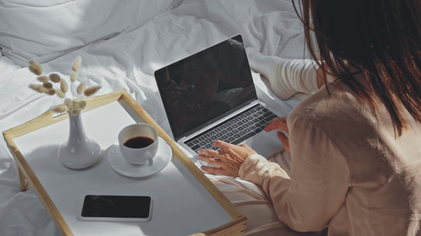 πίσω όψη του freelancer πληκτρολογώντας στο laptop στο κρεβάτι - Πλάνα, βίντεο