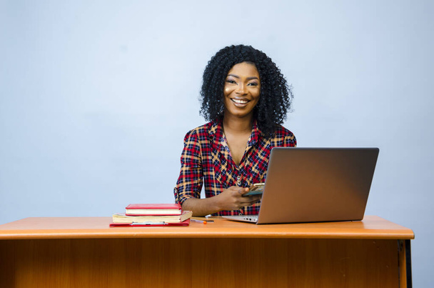Μια όμορφη Αφρο-Αμερικανίδα που κάθεται μπροστά σε ένα λάπτοπ και δουλεύει. - Φωτογραφία, εικόνα
