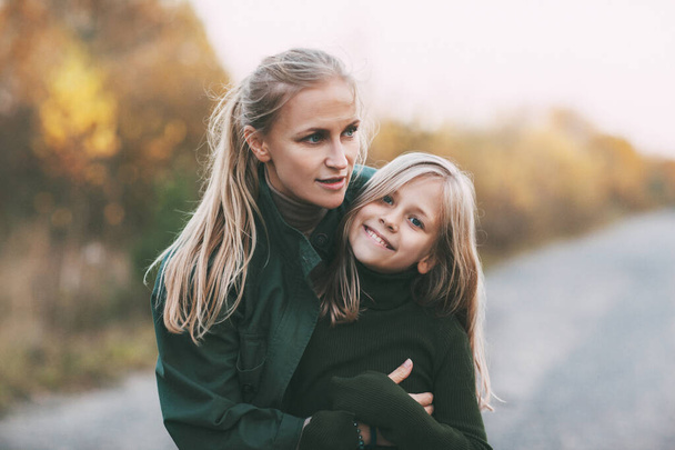 Muotokuva onnellinen kypsä äiti ja hänen blondi pieni tytär halaa ja nauraa kävellessään syksyllä puistossa ulkona. - Valokuva, kuva