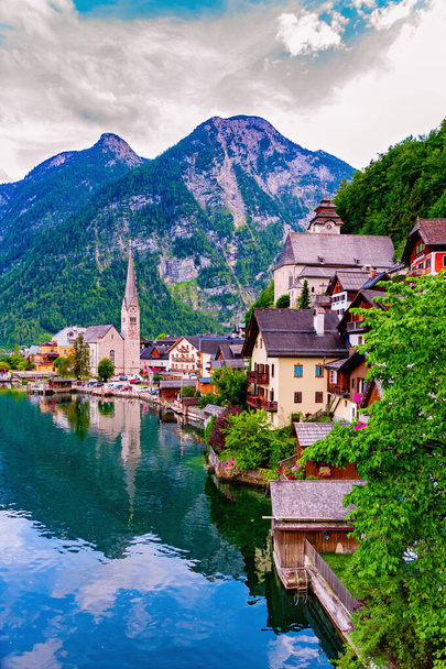 Europe. Austria.View of Holshtatt and Lake Holshtatt.Vertical view.Cloudy summer evening.Hollstatt`s picturesque painting among the mountains.Reflection of the city in the lake.Glare on the water. - Photo, Image