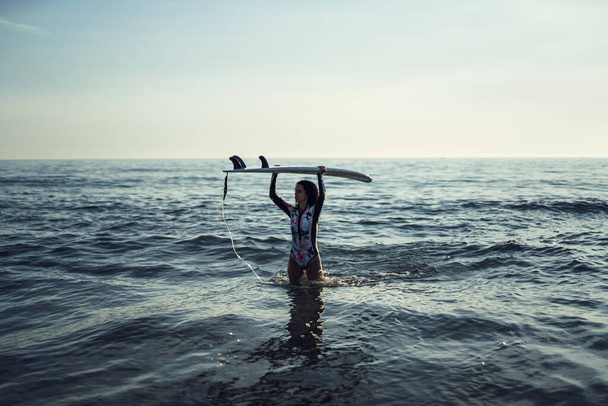 A female and her surfboard by the ocean - Фото, зображення