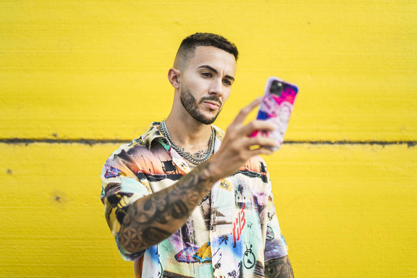 A closeup shot of a young European male with tattoos holding a phone - Foto, Imagen