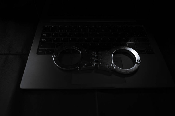 A closeup shot of handcuffs on a laptop keyboard - Fotoğraf, Görsel