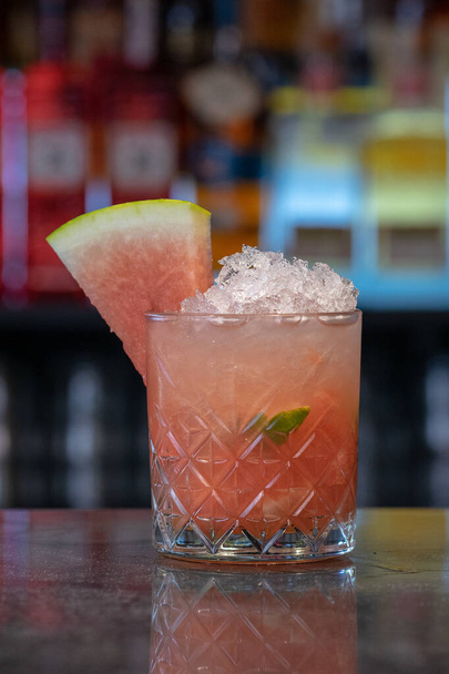 A closeup shot of a glass of iced cocktail with watermelon on a bar counter - Photo, image