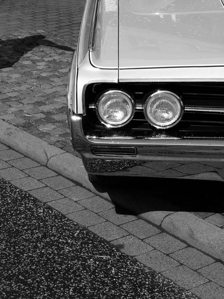 A grayscale closeup shot of American eight-cylinder coupe from the sixties with raindrops shining in the sun - Valokuva, kuva