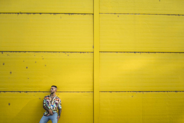A young attractive guy posing in front of a yellow wall - Zdjęcie, obraz