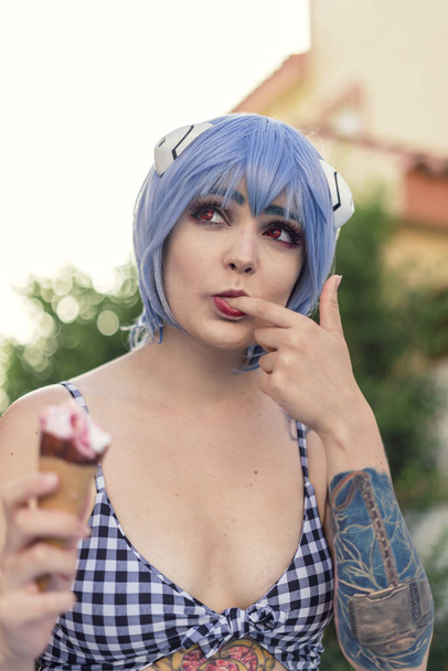A vertical shot of a European female with blue haor eating an ice-cream - Foto, imagen