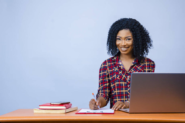 A pretty Afro-American female sitting in front of a laptop and working - 写真・画像