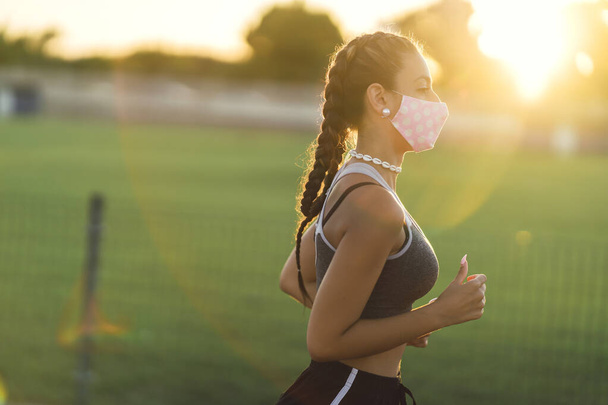 A young athletic woman runner wearing a medical protective mask - Foto, Imagen