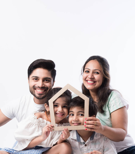 Familia india Padre, madre, hijo e hija sosteniendo el modelo de papel 3D del hogar - Real Istate Concept in India - Foto, imagen