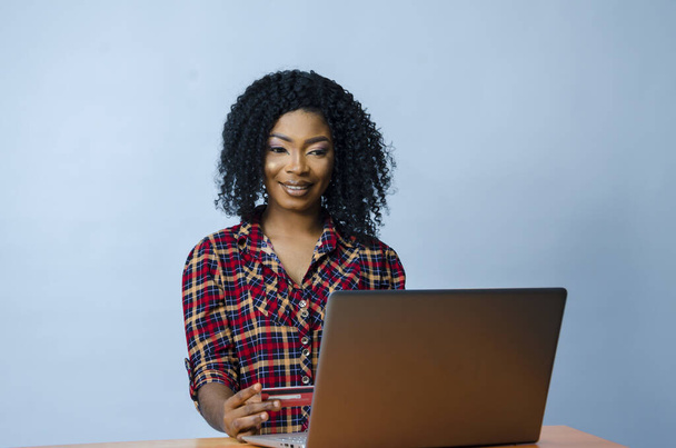 A pretty Afro-American female sitting in front of a laptop and working - Foto, Bild