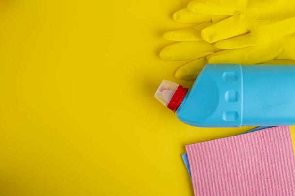 Cleaning set from a blue bottle, rubber gloves and a sponge on a yellow background. Cleanliness concept. Space for text. Top view. - Fotoğraf, Görsel