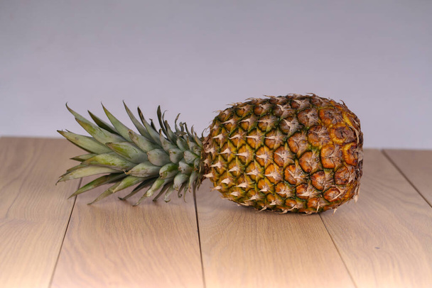 A closeup of a whole pineapple on a wooden table - Fotoğraf, Görsel