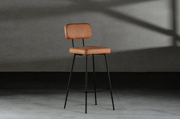 A closeup of a high stool with leather upholstery, on thin legs, loft-style furniture - Zdjęcie, obraz