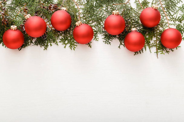 Christmas composition made of red bauble decorations, fir tree branches on white wooden table background. Christmas, Xmas, winter, new year concept. Flat lay, top view, copy space. - Fotografie, Obrázek