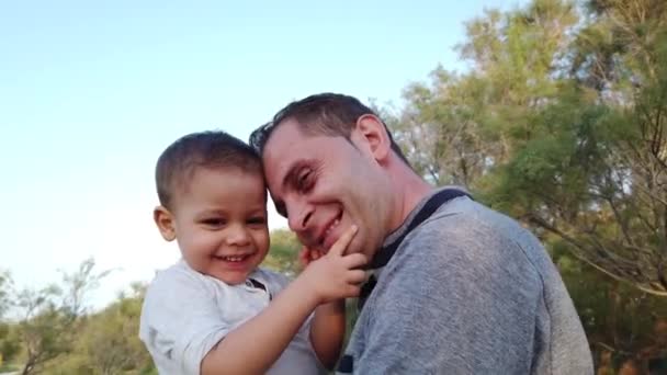 Fiatal kaukázusi apa, kezében a kisfiával. A baba megérinti az apja arcát. - Felvétel, videó