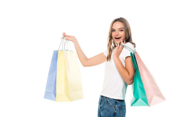young excited woman holding colorful shopping bags and looking at camera isolated on white - Foto, Bild