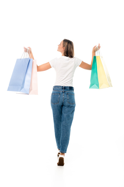 back view of young woman in jeans holding shopping bags isolated on white  - Foto, immagini