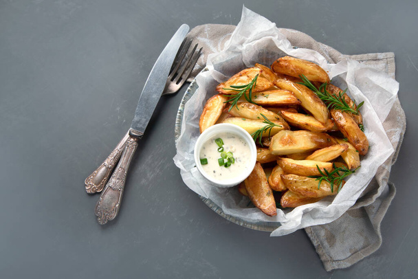Baked country style potato wedges with herbs and sauce.  - Фото, изображение