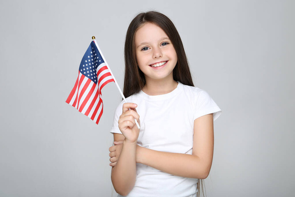 Jovencita sosteniendo bandera americana sobre fondo gris - Foto, imagen