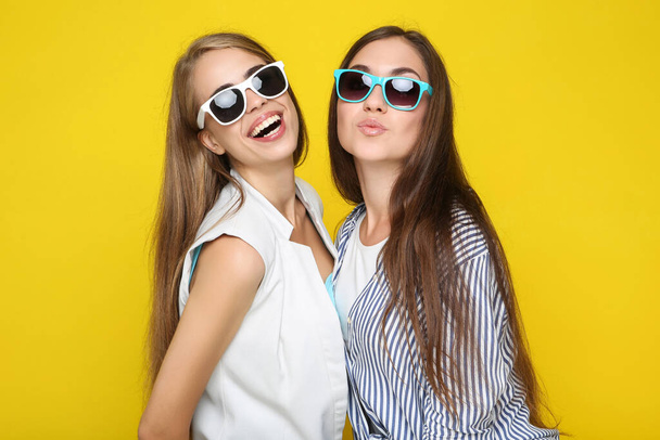 Young happy girlfriends in sunglasses on yellow background - Foto, Imagem